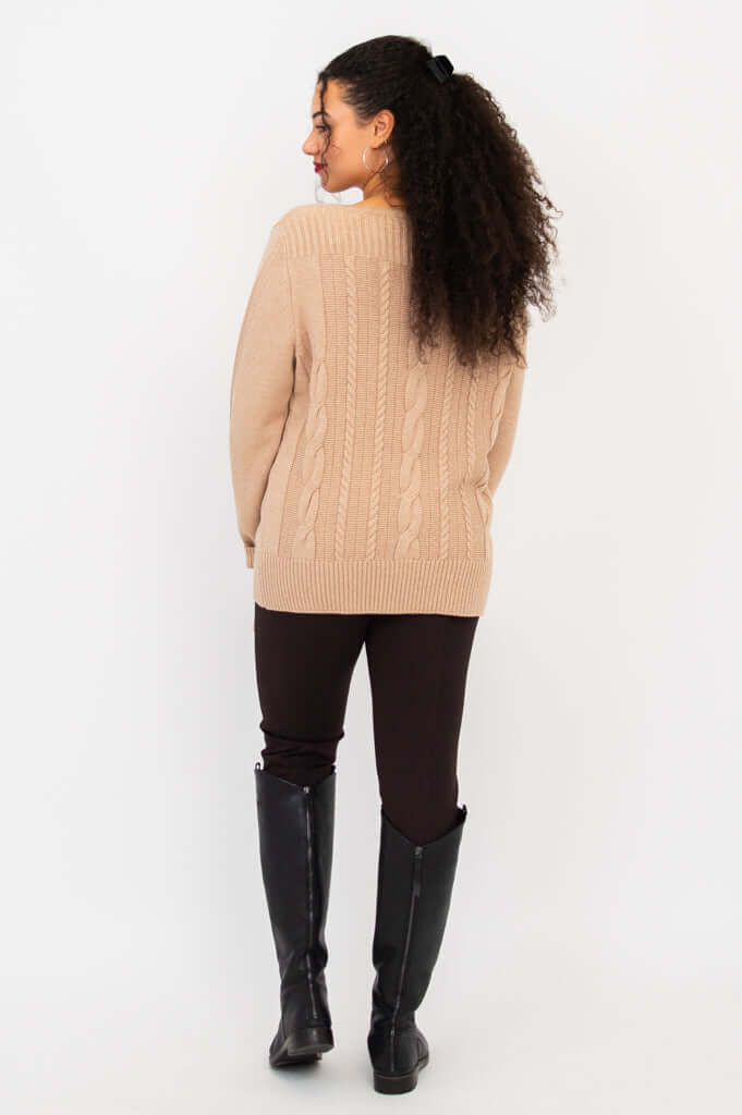 Rear view of woman wearing beige cable knit sweater and black boots