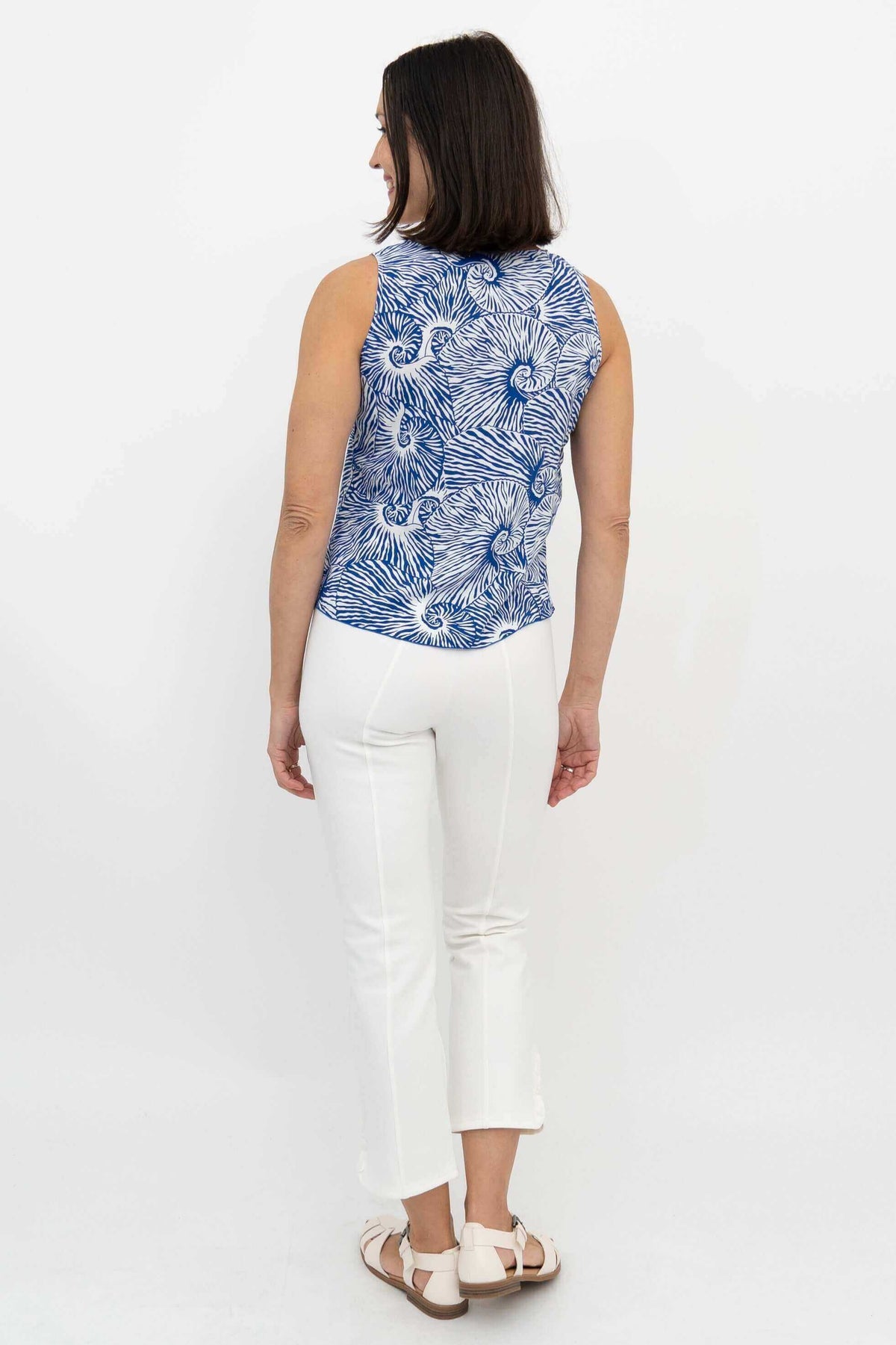 Back view of woman wearing the Dee Tank blue swirl print top with white pants