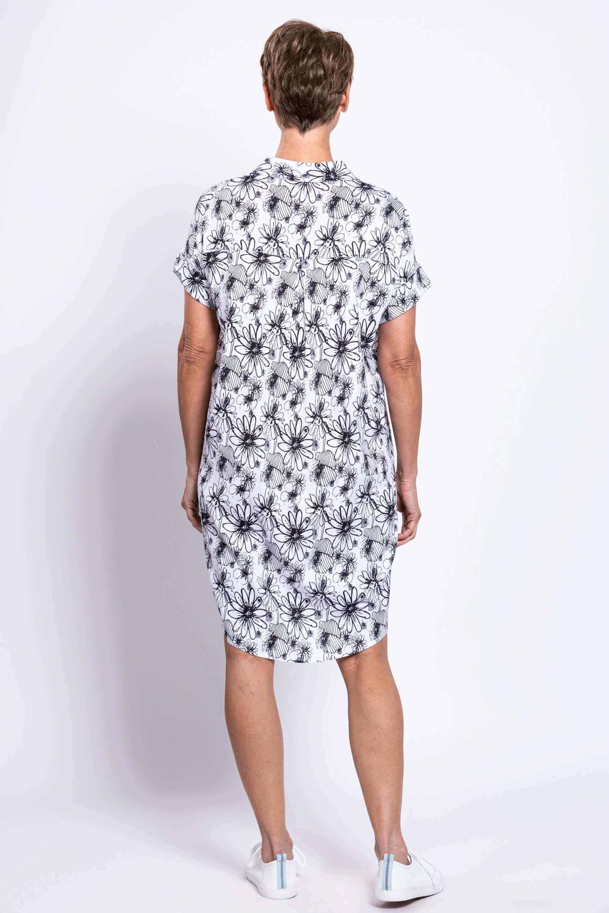 Back view of a woman in a black and white floral shirt dress with cuffed sleeves