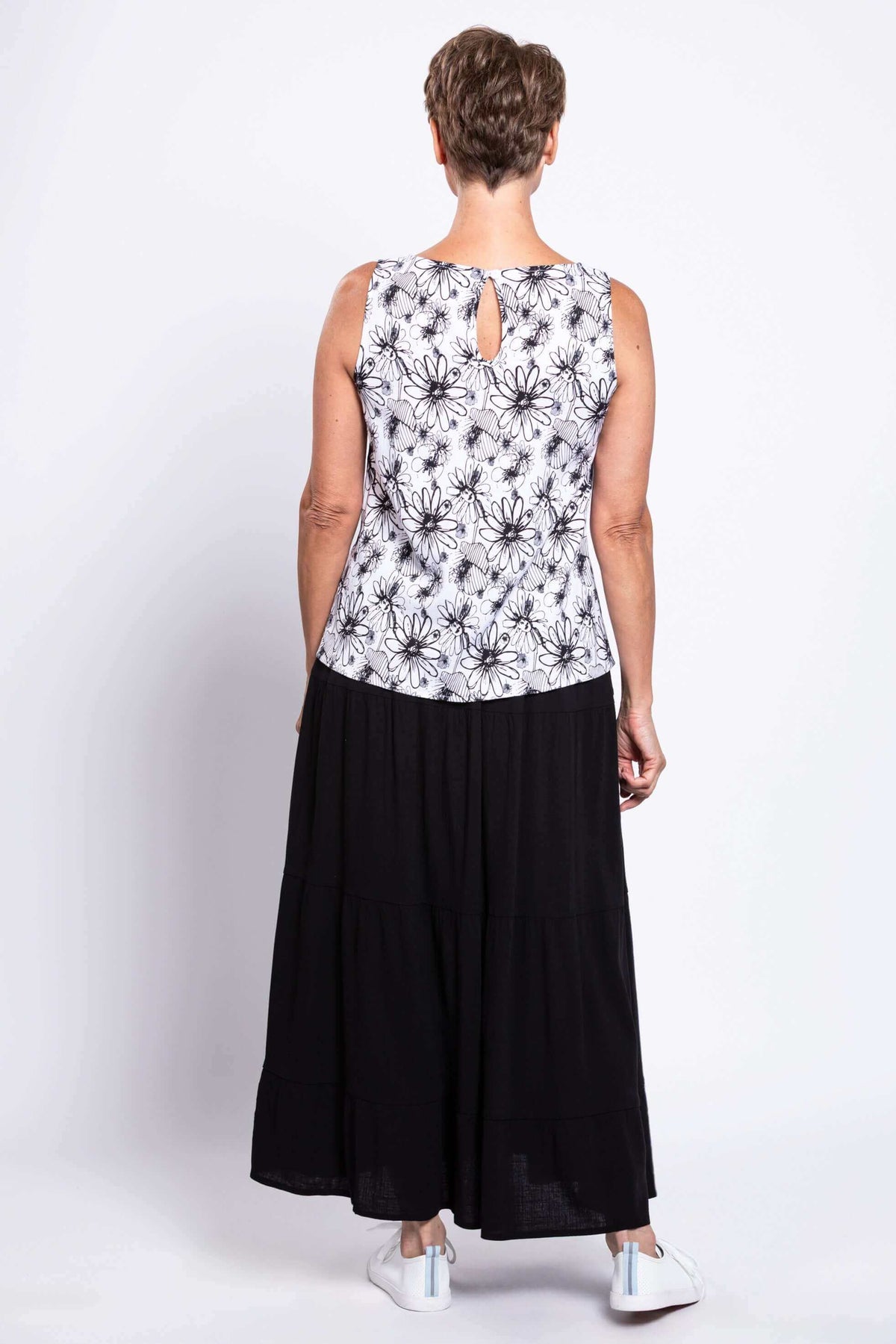 Back view of a woman in a black and white floral tank top showing the button closure