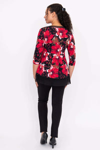 Back view of woman wearing red floral top with black mesh hem and black pants