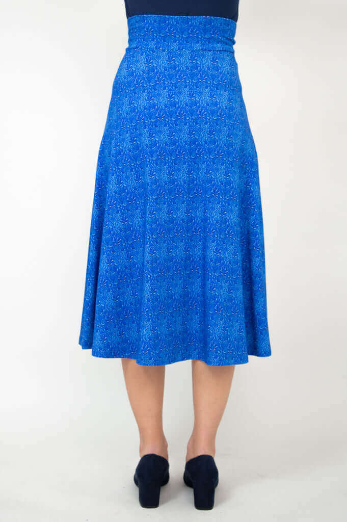 Back view of a woman wearing a blue patterned stretch skirt with mid-calf hem