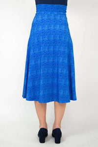 Back view of a woman wearing a blue patterned stretch skirt with mid-calf hem
