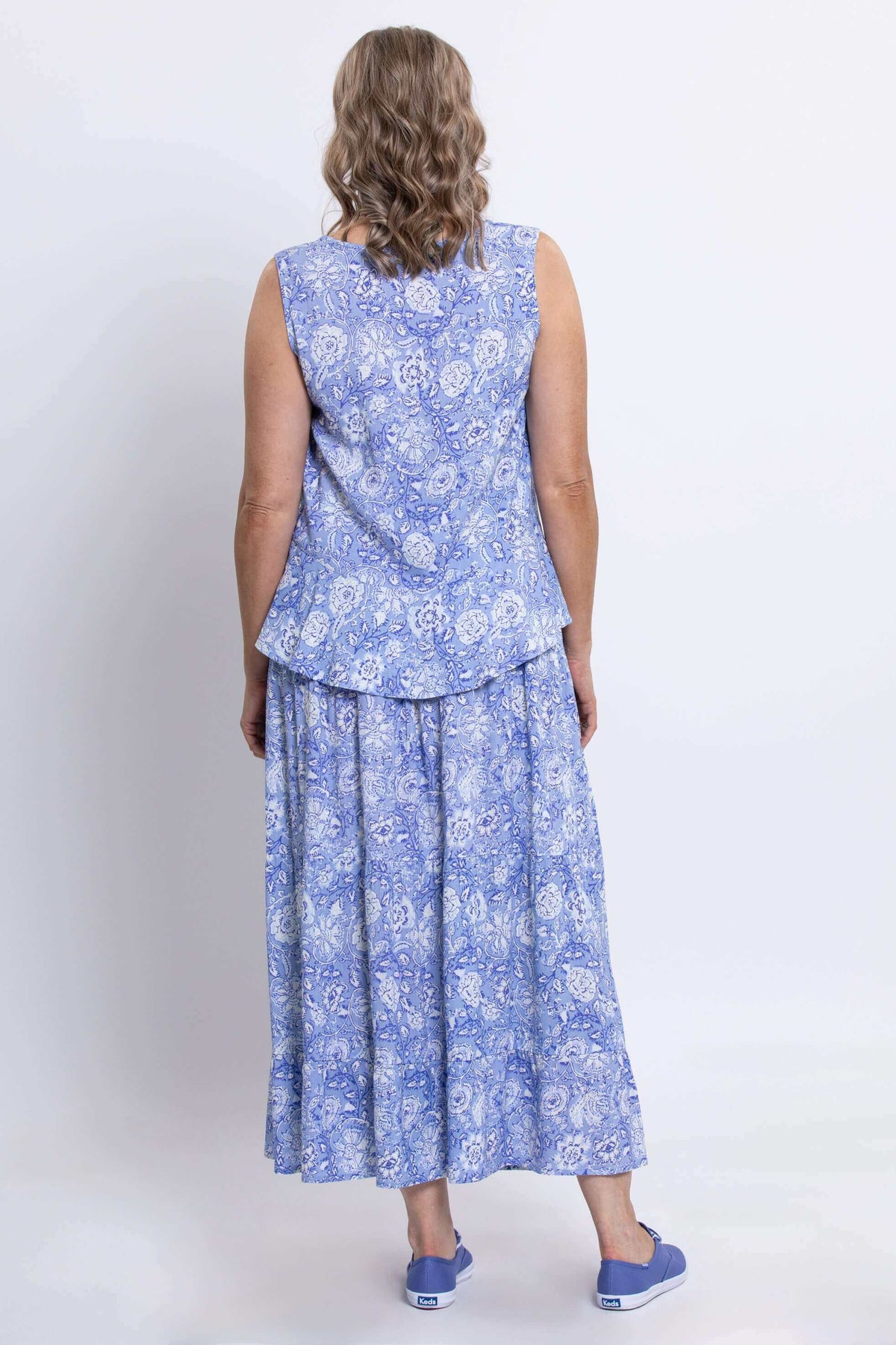 Back view of woman wearing sleeveless periwinkle floral Ginny Tank and matching skirt