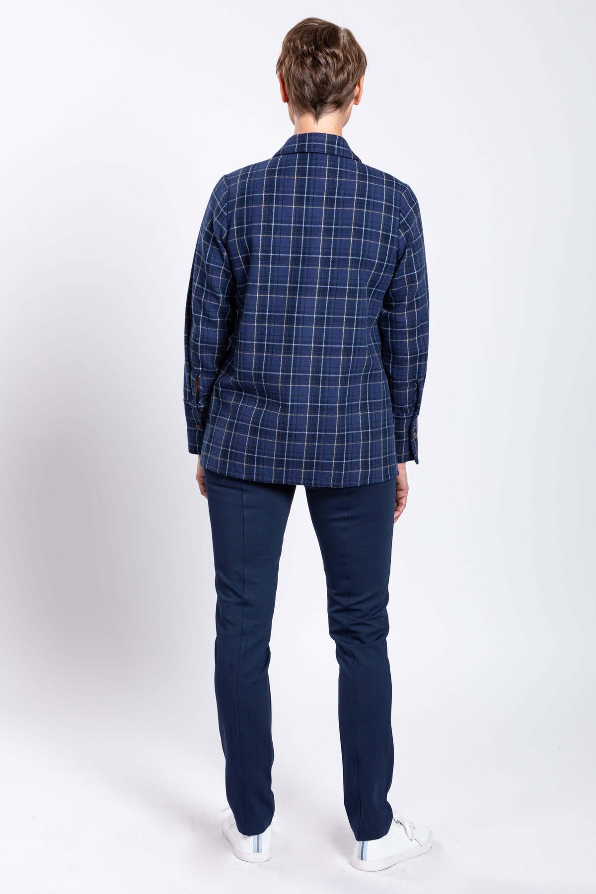 Back view of a woman in a blue plaid cotton jacket and navy pants