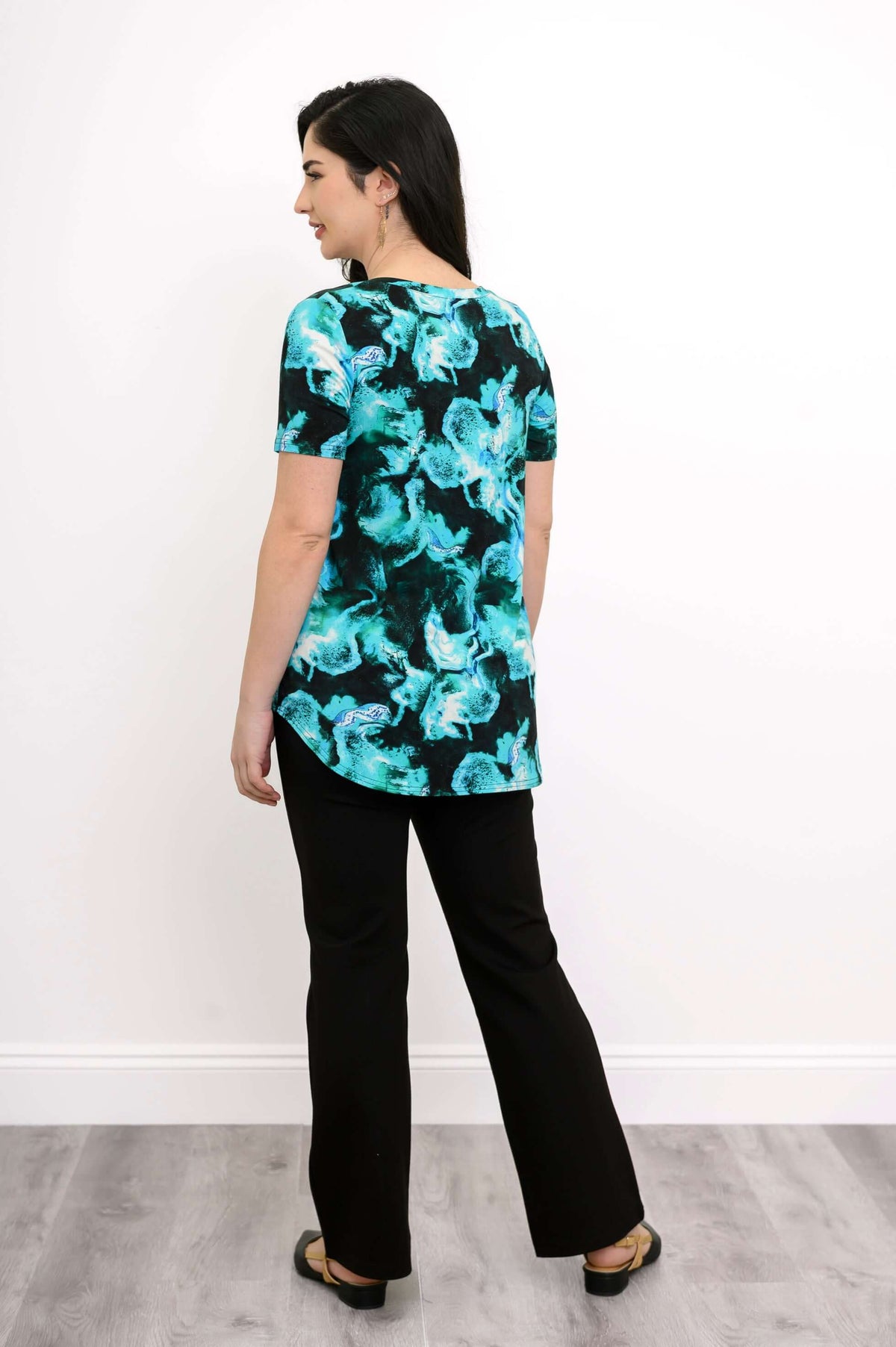 Back view of woman modeling short sleeve blouse with neon turquoise swirl print