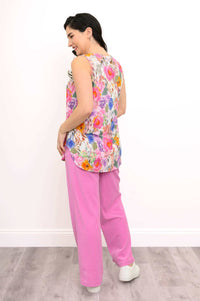 Back view of woman modeling sleeveless top with rounded hemline and pink pants