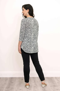 Back view of model wearing 3/4 sleeve floral top and black pants against a white background