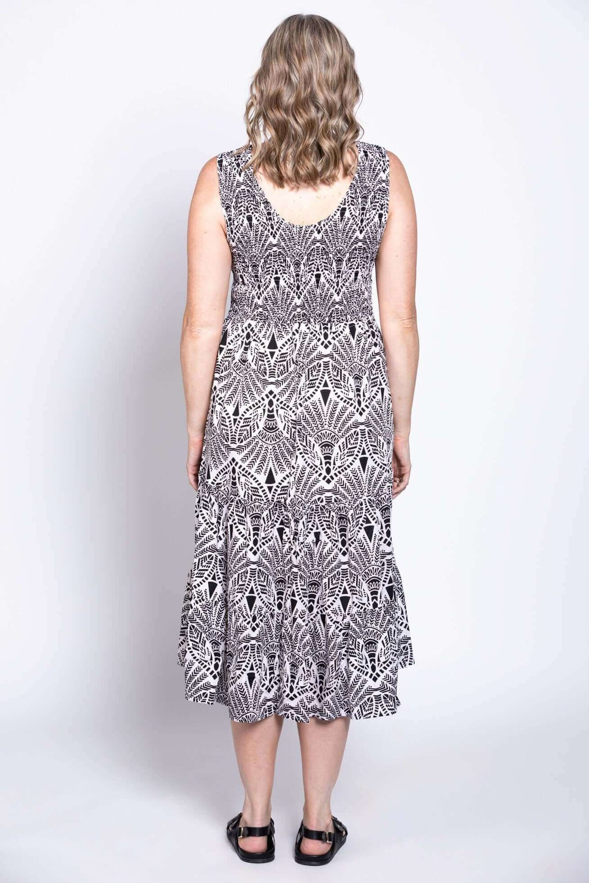 Back view of woman in sleeveless black and white patterned tiered dress