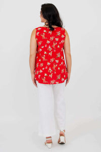 Back view of woman in red floral sleeveless tank top and white pants
