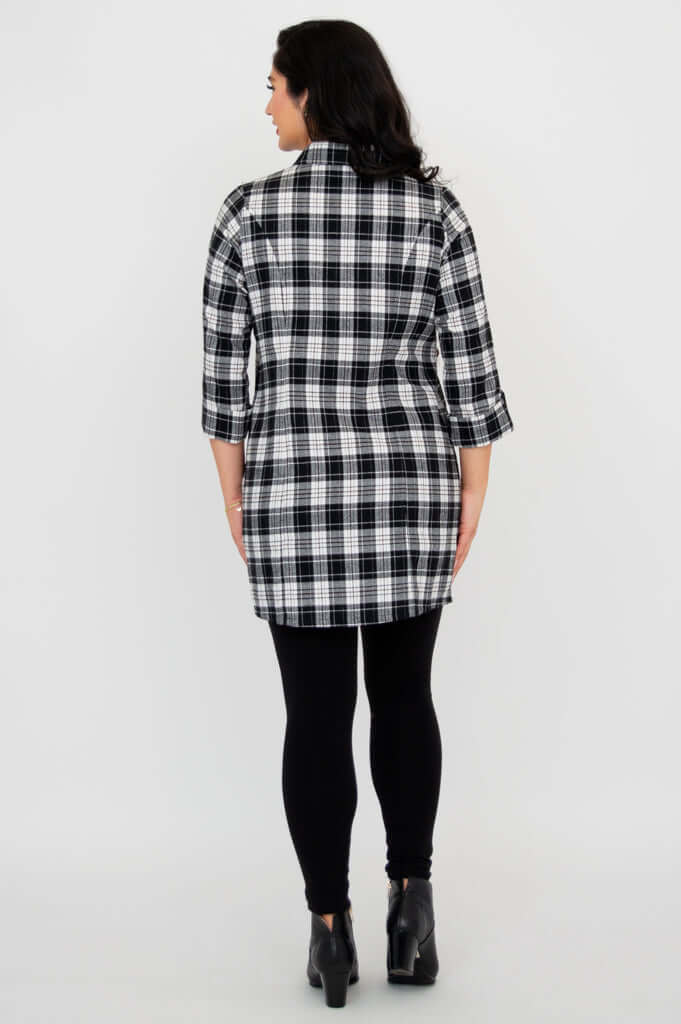 Back view of model wearing a black and white plaid flannel tunic and black leggings