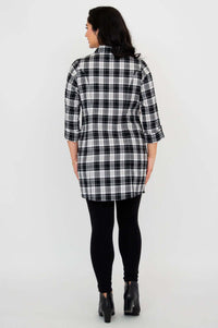 Back view of model wearing a black and white plaid flannel tunic and black leggings