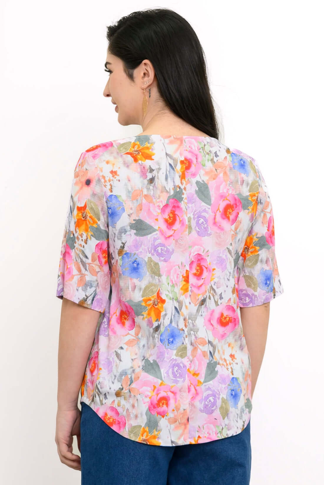 Back view of woman wearing half-sleeve blouse with rounded hemline and pink multicolor floral print