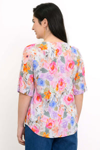 Back view of woman wearing half-sleeve blouse with rounded hemline and pink multicolor floral print
