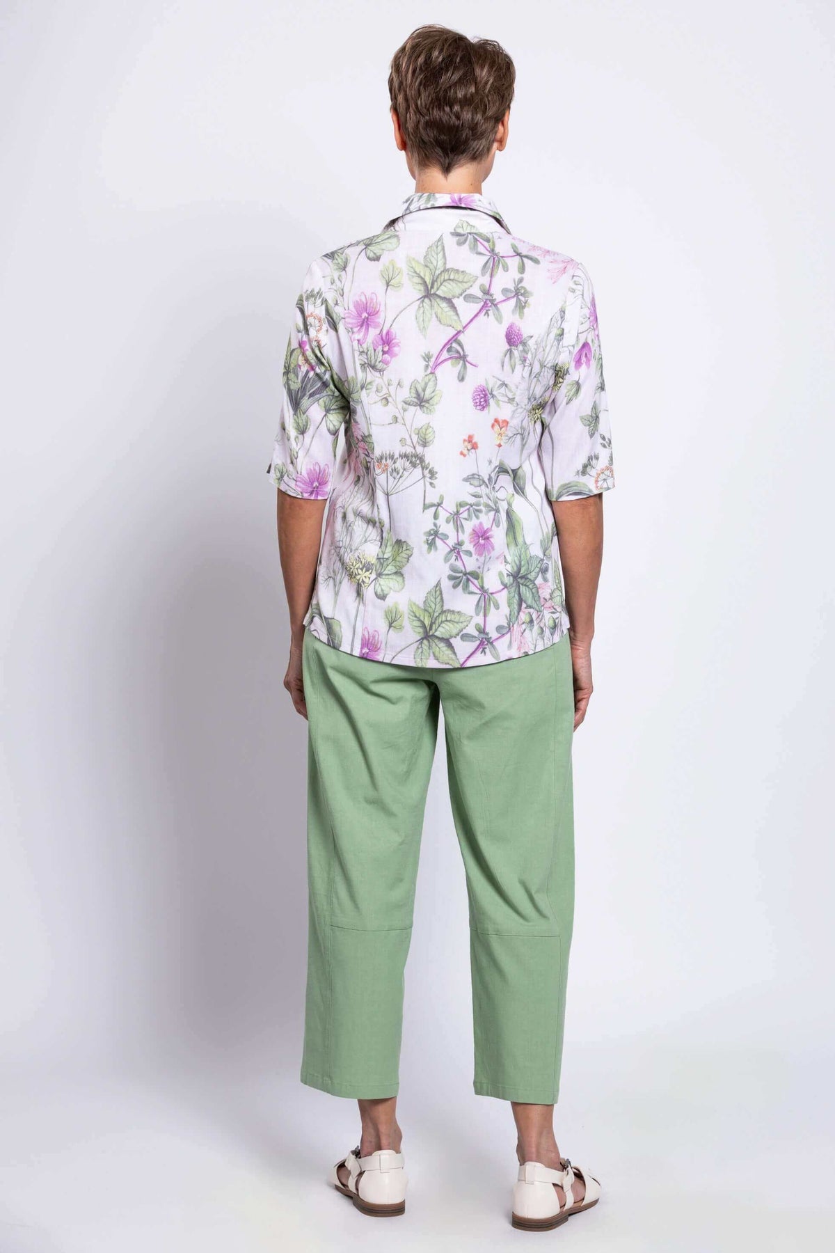 Back view of woman modelling half-sleeve botanical print top and pastel green pants