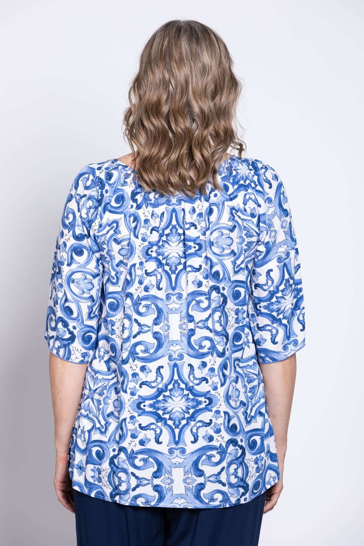 Back view of a woman showing the blue and white tile print peasant top
