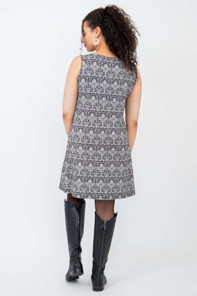 Back view of model in sleeveless shift dress showcasing allover patterned fabric and A-line cut