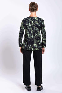 Back view of woman wearing forest abstract long-sleeve top and black pants