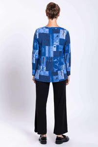 Back view of blue patchwork long-sleeve top worn by a woman with black pants