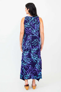 Back view of a woman in a sleeveless navy dress with teal and purple abstract leaves