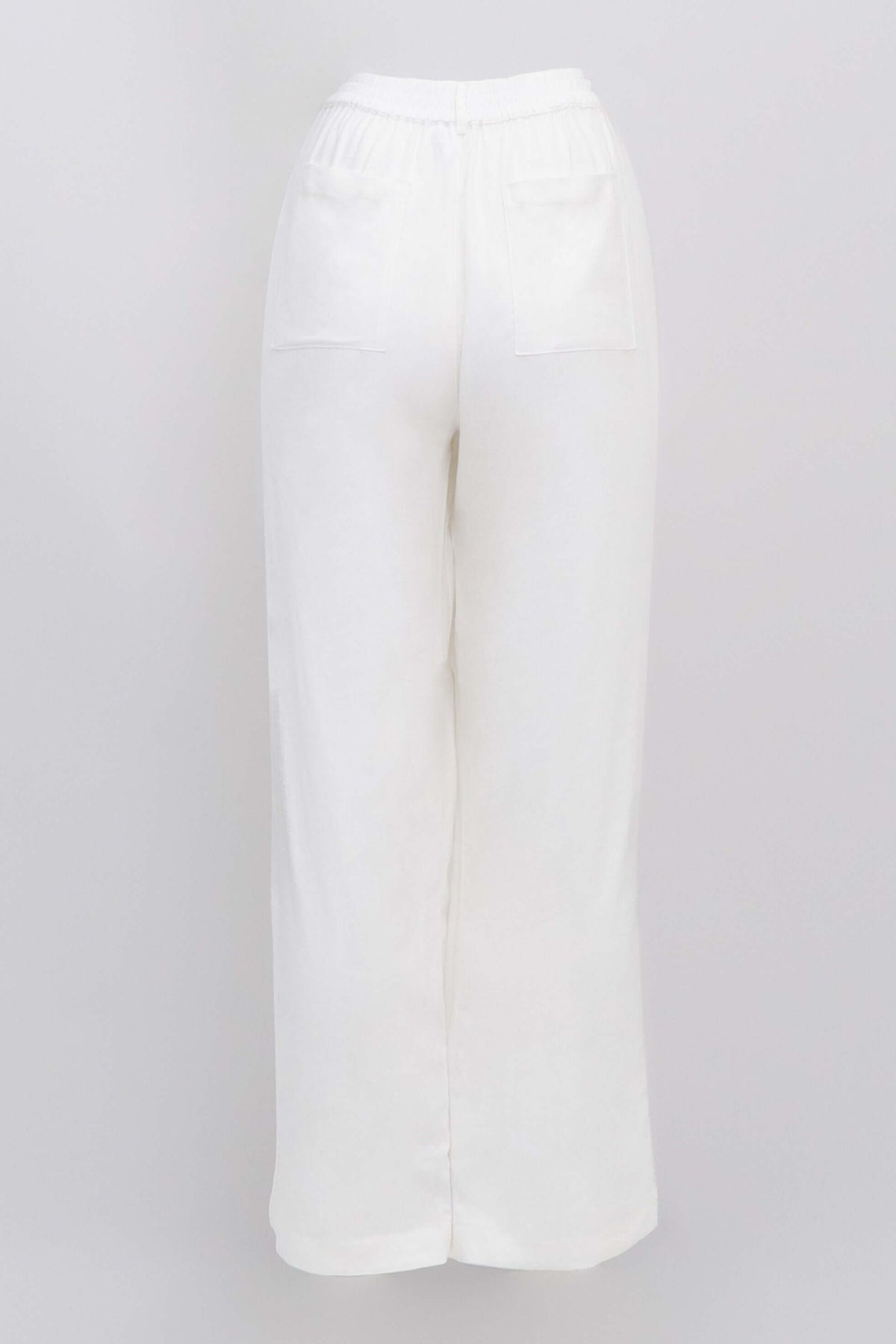 Back view of white trousers against a white background featuring elastic waistband and pockets