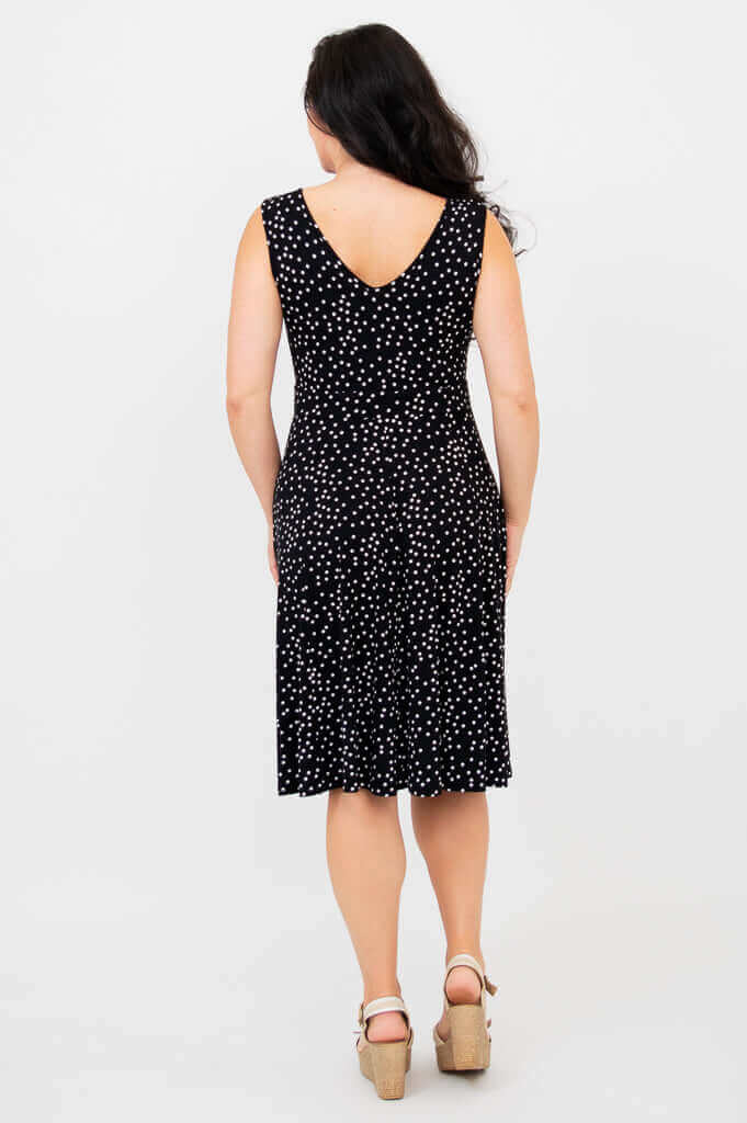 Back view of woman wearing a sleeveless black dress with white polka dots