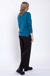 Back view of a woman in black wide-leg pants and a teal sweater