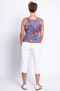 Back view of woman wearing blue floral reversible bamboo tank top with white pants