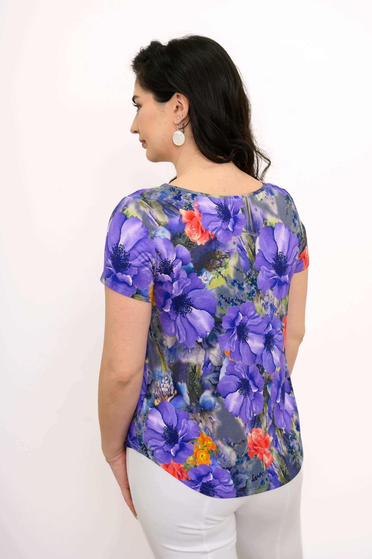Back view of woman wearing short sleeve top with rounded hemline and multicolor floral pattern