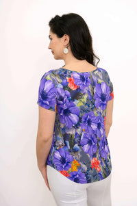 Back view of woman wearing short sleeve top with rounded hemline and multicolor floral pattern