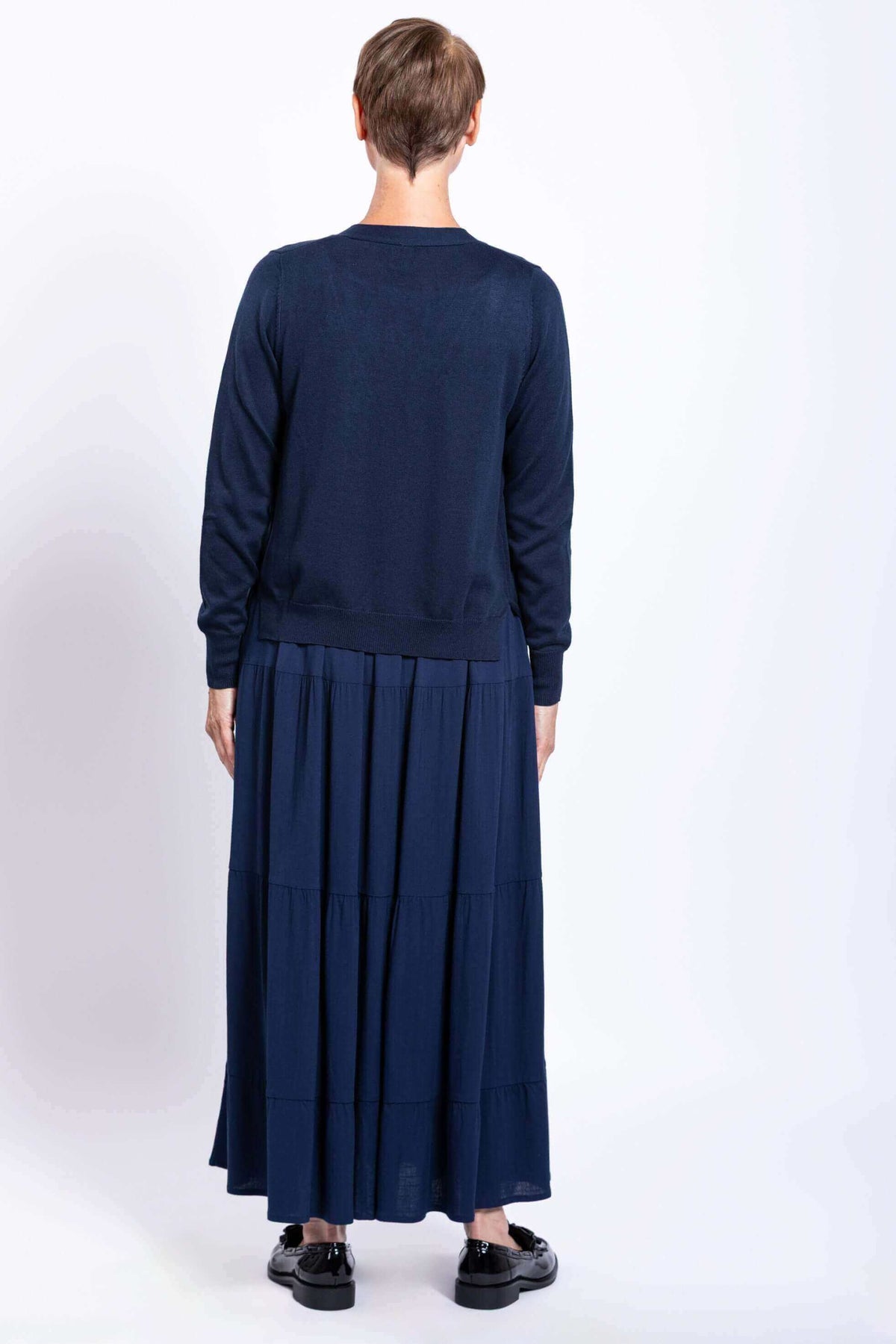 Back view of model wearing navy tiered maxi skirt and navy cardigan