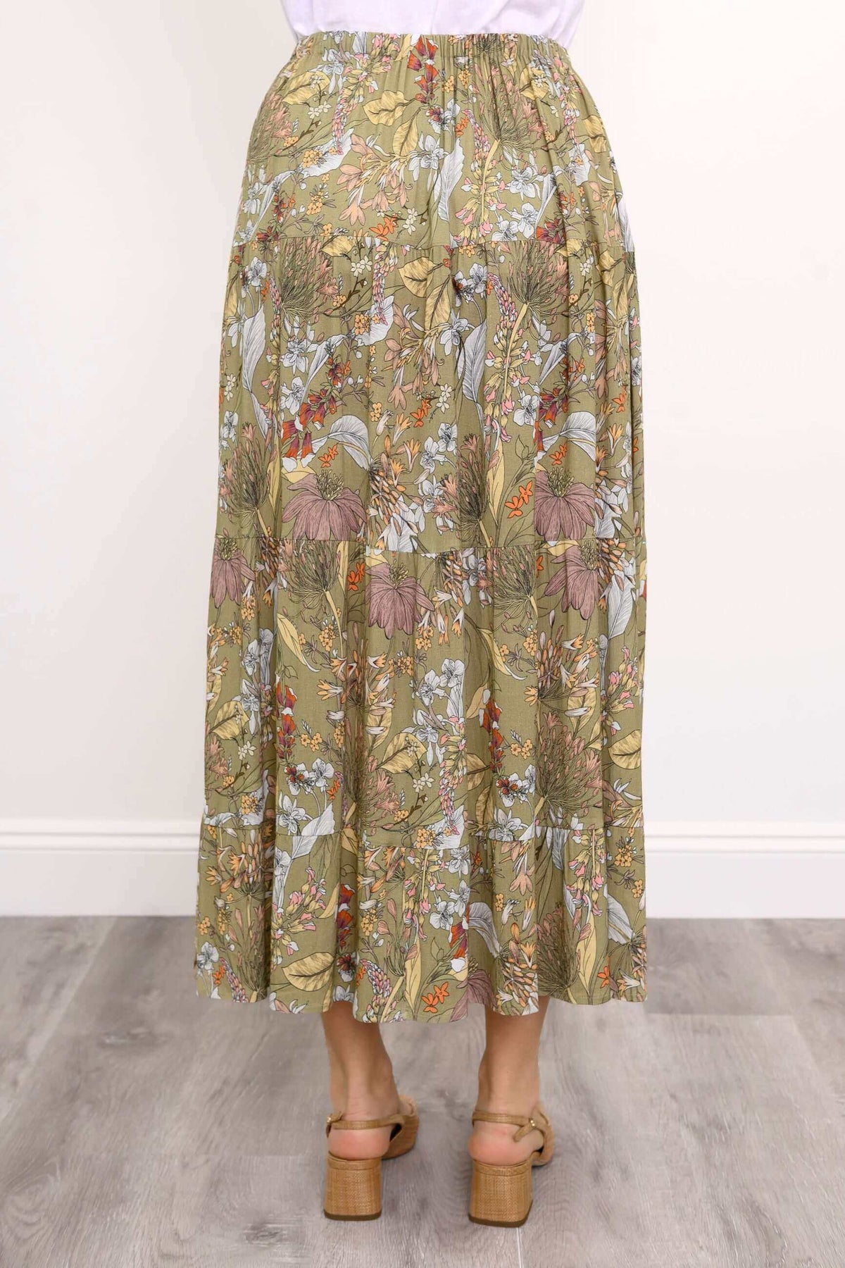 Back close-up view of woman wearing tiered ruffle skirt with elastic waistband and khaki floral pattern