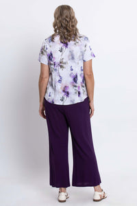 Back view of a woman wearing a short-sleeve purple floral print blouse and purple pants