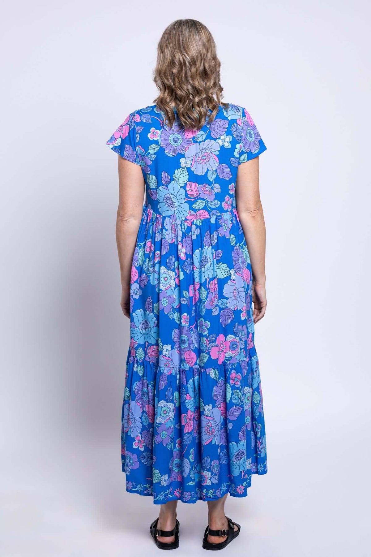 Back view of a woman wearing the blue floral Sharpie maxi dress