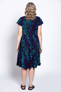 Woman wearing a black dress with blue and purple print, back view showing tiered skirt