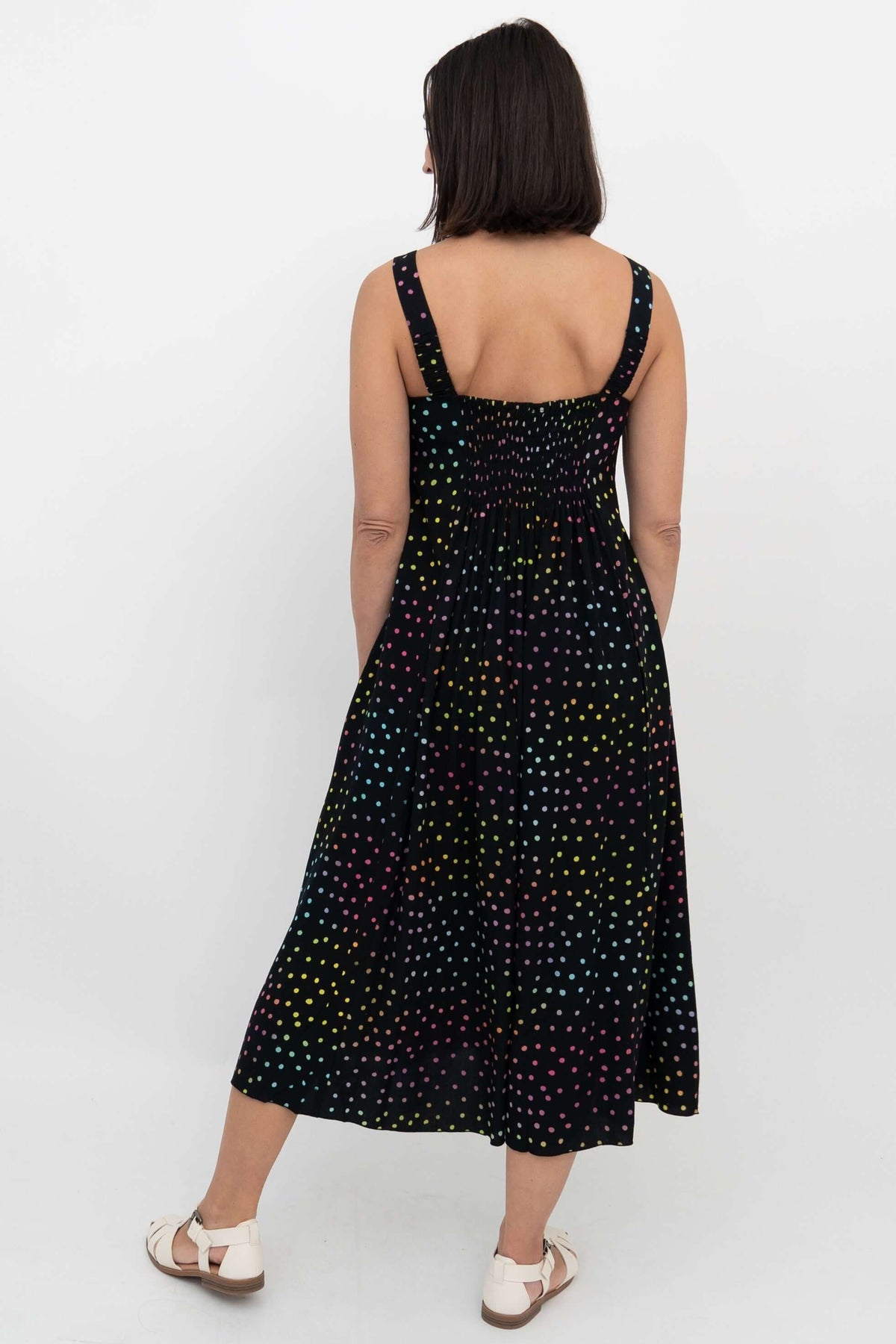 Back view showing shirred bodice and wide straps of black polka dot midi dress