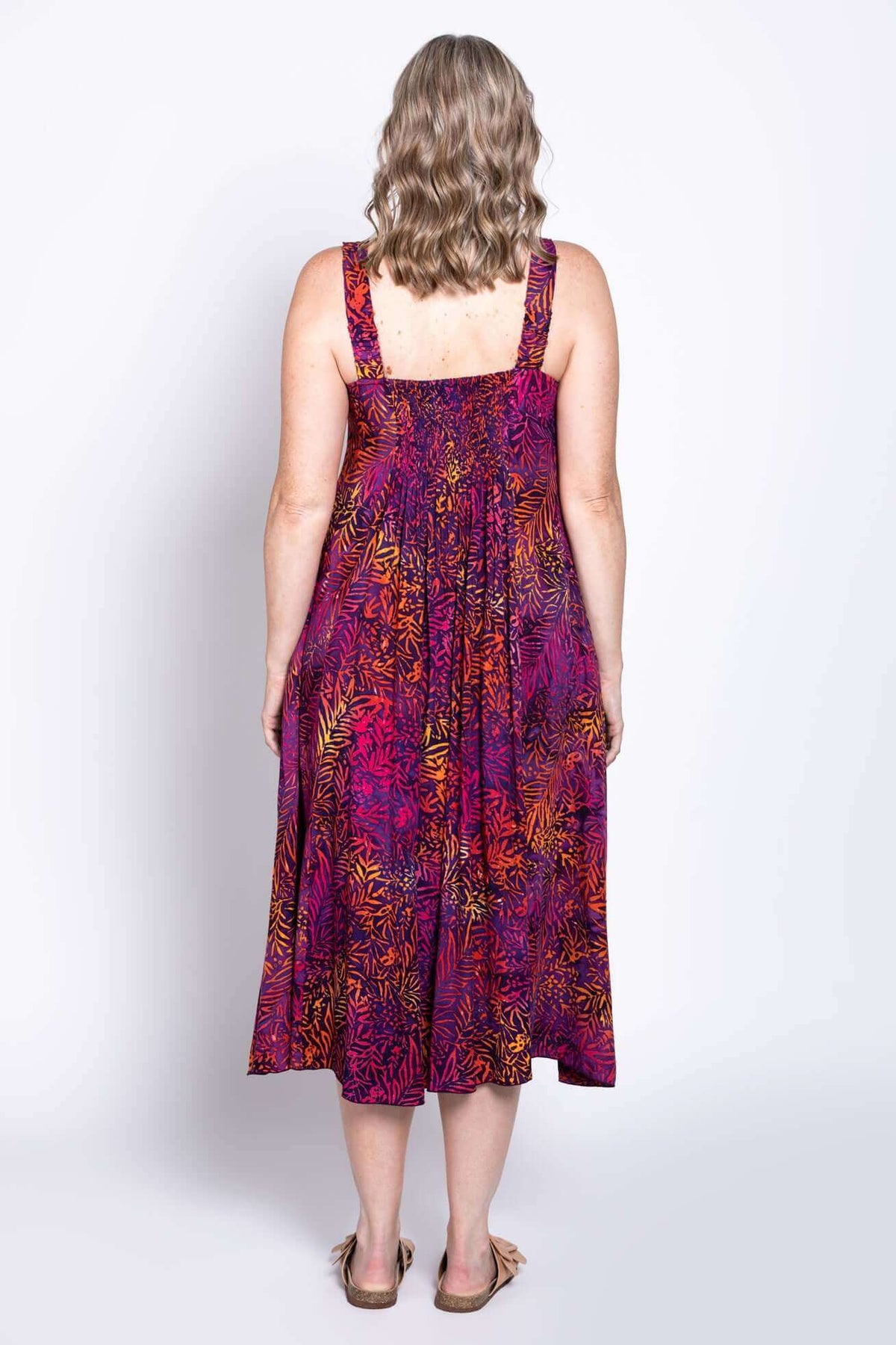 Back view of woman wearing a colorful empire waist dress with wide straps