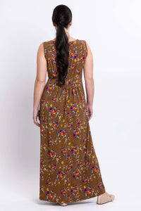 Back view of a woman wearing a brown maxi dress with vivid floral print and pleating