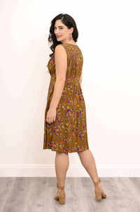 Woman showing the back pleat detail of a brown floral sleeveless dress