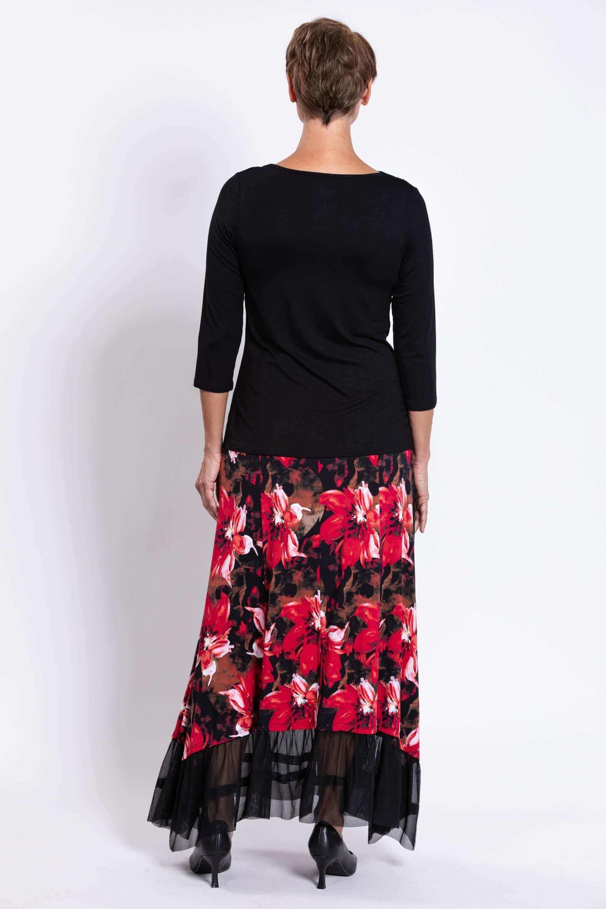 Back view of woman in black top and red floral Vera Maxi Skirt with black mesh hem