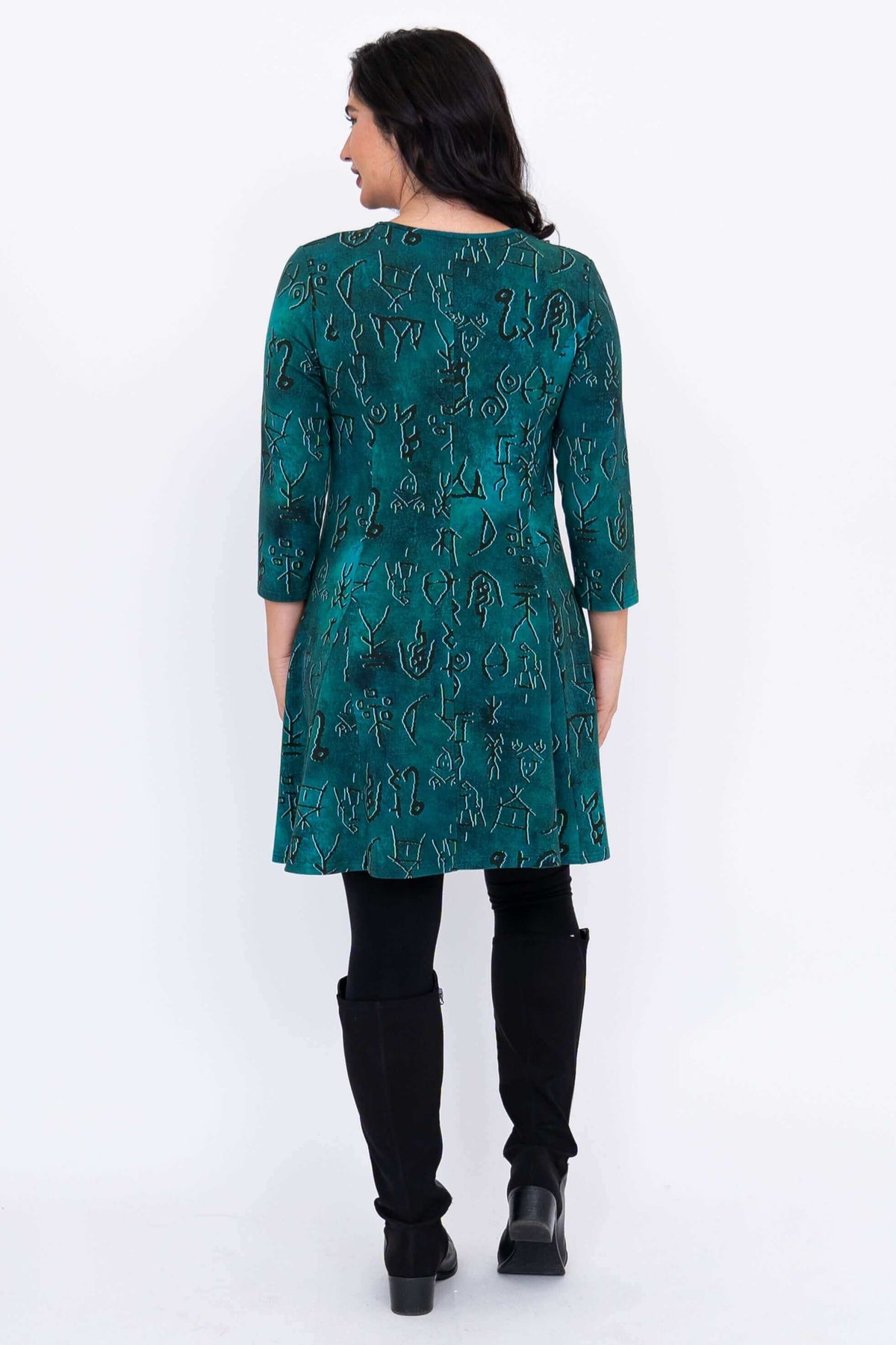Rear profile shot of a long sleeve teal patterned fit and flare tunic displaying clean back seams.