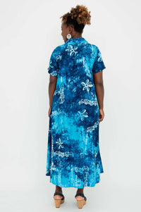 Back view of a woman in a blue batik short sleeve dress, standing