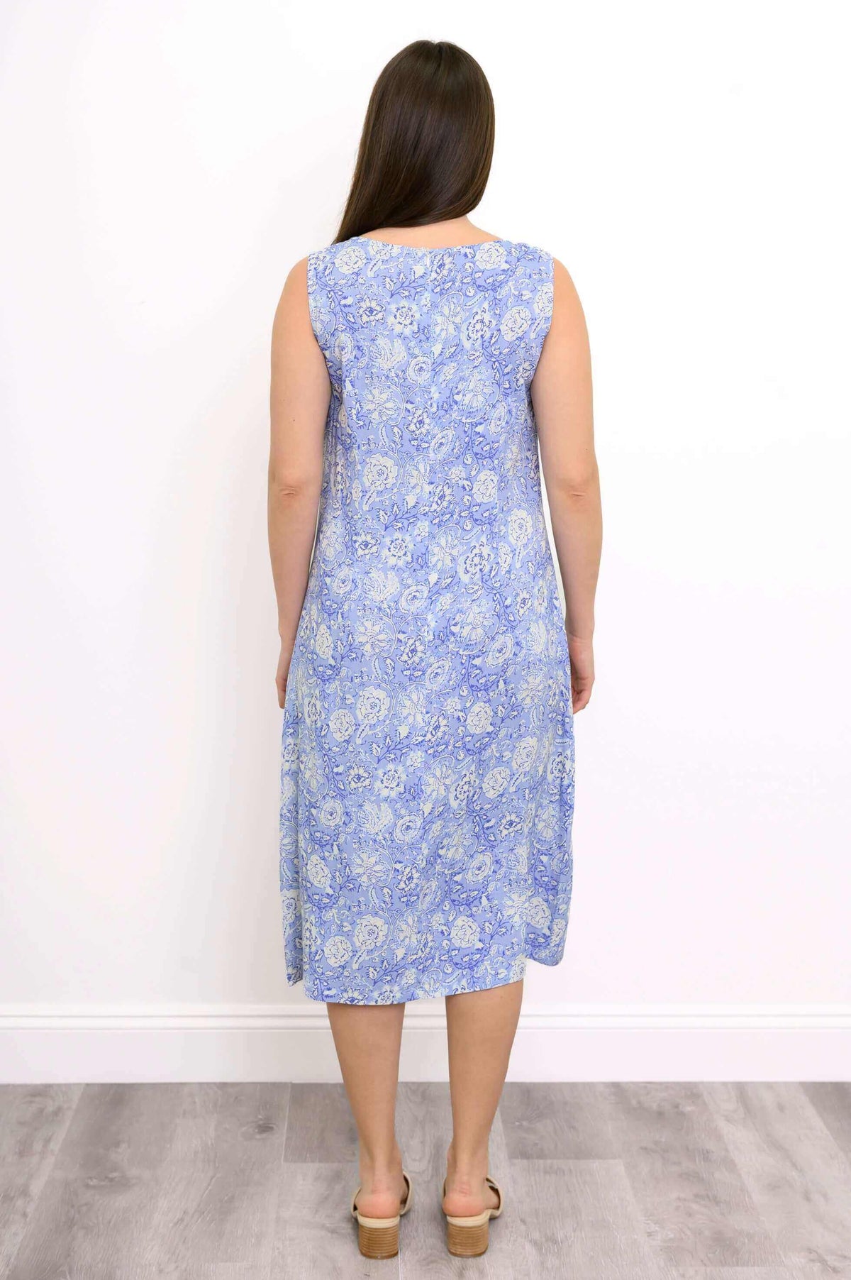 Back view of a woman in a blue floral sleeveless dress with straight hair