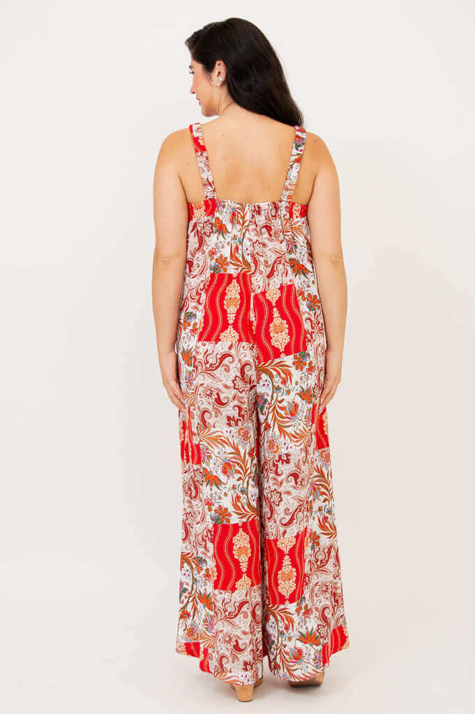 Back view of a woman in a red and cream patterned wide-leg jumpsuit