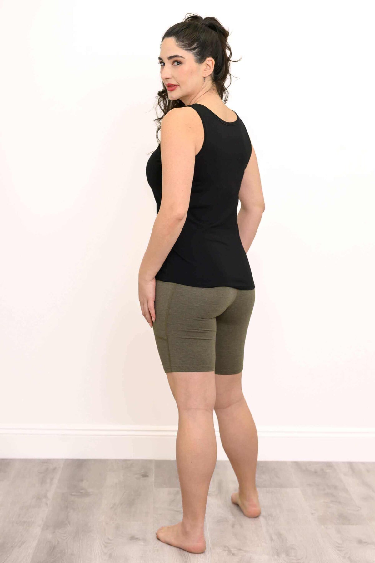 Back view of a woman in olive green shorts and black tank top