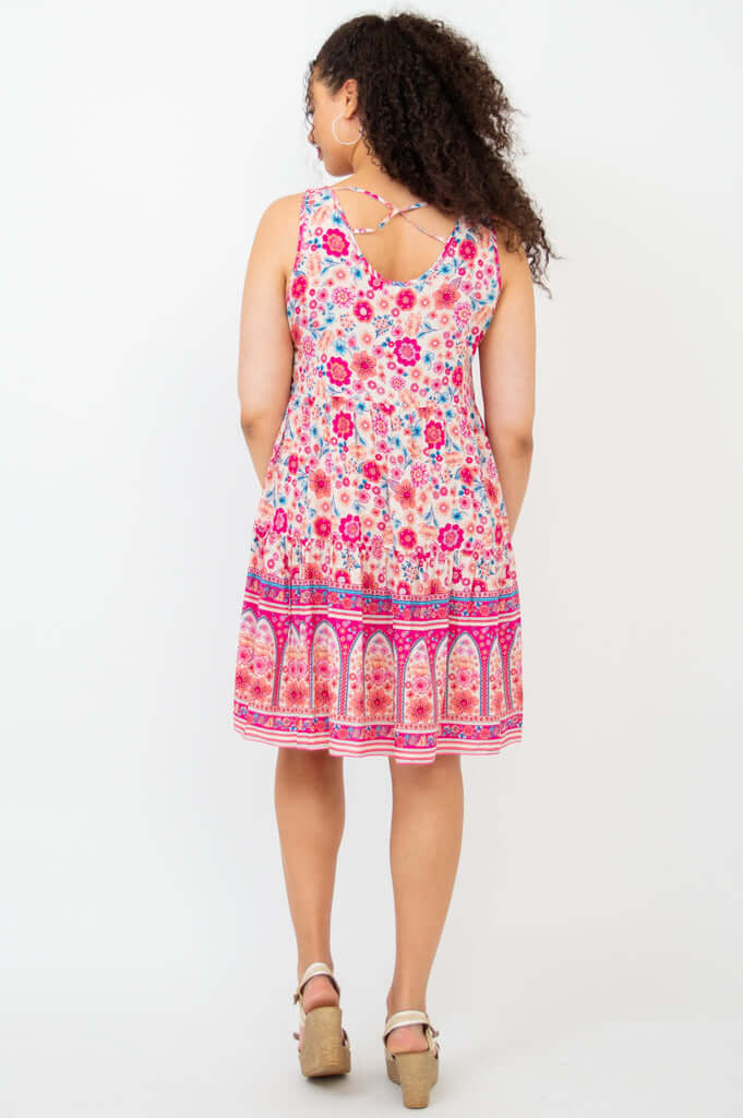 Back view of a woman wearing a criss-cross strap pink floral tiered dress