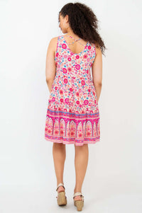 Back view of a woman wearing a criss-cross strap pink floral tiered dress