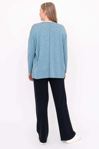 Back view of a woman wearing a light blue merino wool sweater and black pants