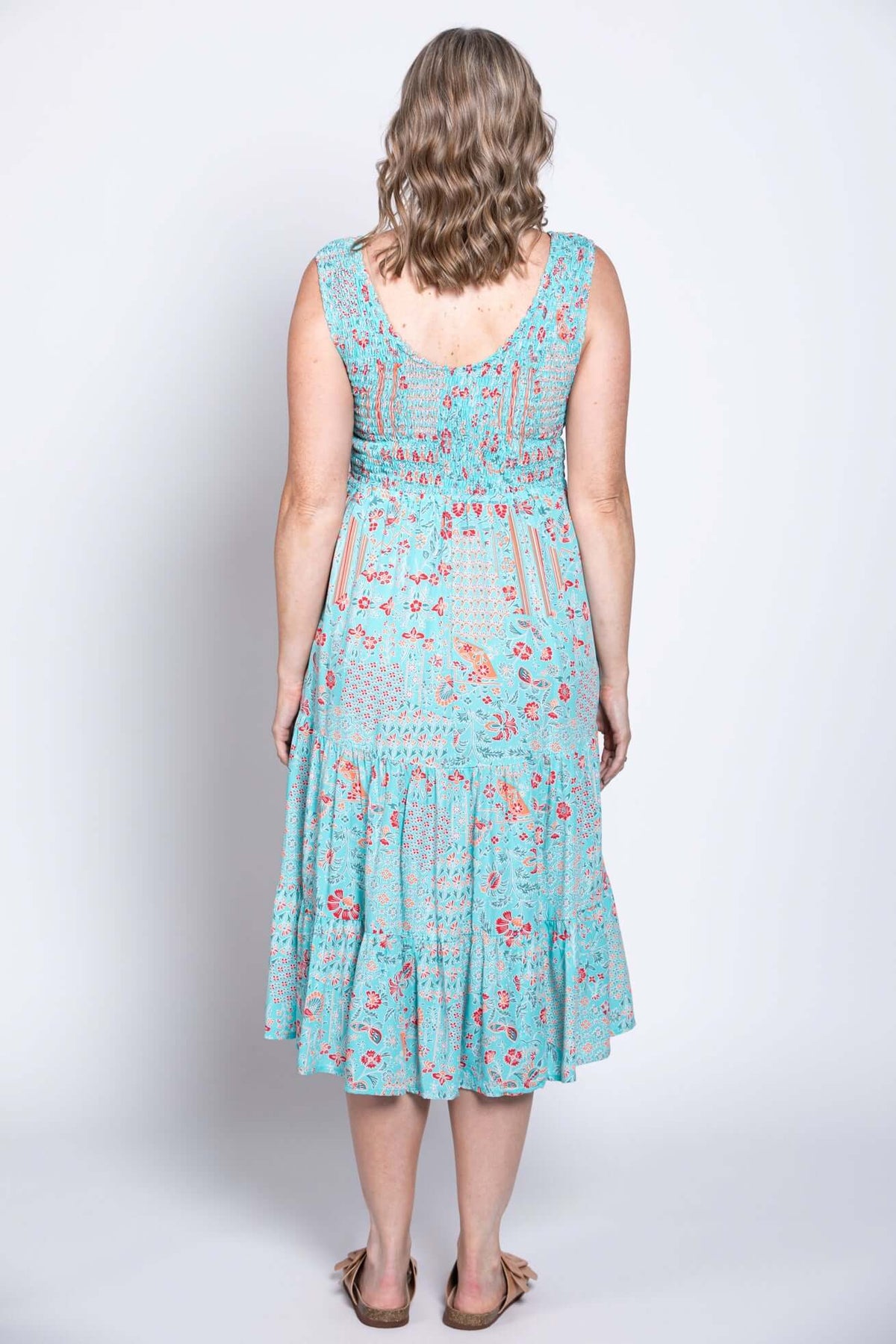 Back view of a woman wearing a light blue tiered sleeveless floral midi dress