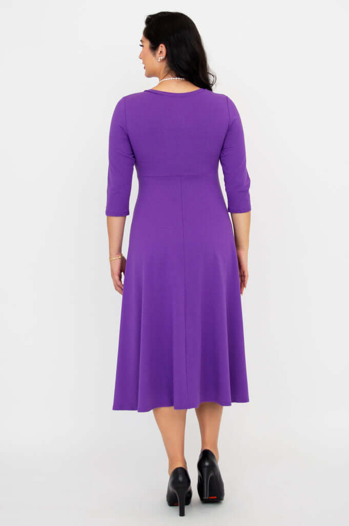 Back view of a woman wearing a purple midi dress showing seam details and silhouette
